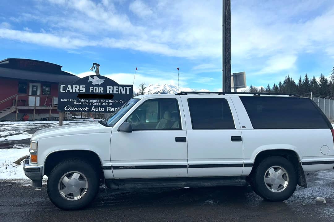 Cars for Rent = Don't keep fishing around for a rental car - hook into a good deal at Chinook Auto Rental - sign behind a white SUV