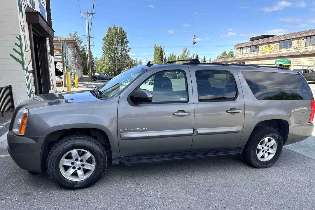 Shiny silver yukon xl parked in town under blue skies